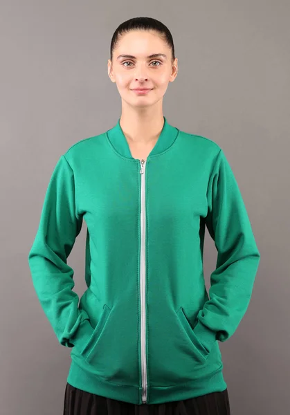 Young hipster girl wearing blank green lime cotton zip up sweatshirt with copy space for your design or logo, mock-up of ltemplate womens hoodie, grey wall in the background