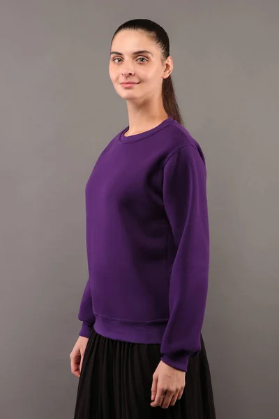 Menina jovem hipster vestindo camisola de algodão roxo em branco com espaço de cópia para o seu design ou logotipo, mock-up de capuz modelo roxo das mulheres, parede cinza no fundo — Fotografia de Stock