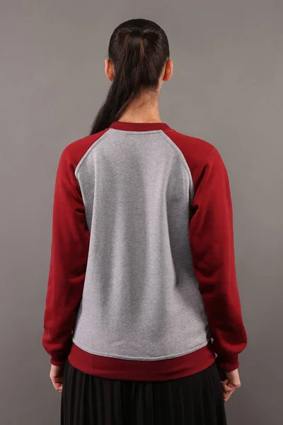 Back of Young hipster girl wearing blank grey and burgundy cotton sweatshirt with crew neck and raglan sleeves with copy space for your design or logo, mock-up of ltemplate womens hoodie