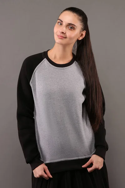 Young hipster girl wearing blank grey and black cotton sweatshirt with crew neck and raglan sleeves with copy space for your design or logo, mock-up of ltemplate womens hoodie