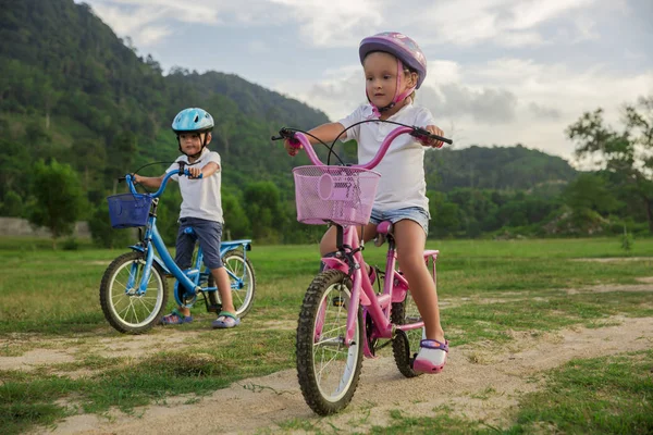 Двое детей на велосипеде. Дети в шлеме на велосипеде в парке. Красивые дети . — стоковое фото