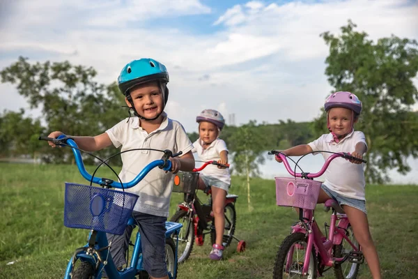 Трое детей на велосипеде. Дети в шлеме на велосипеде в парке. Красивые дети. Закрыть — стоковое фото