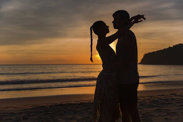 Gli amanti romantici che si abbracciano al crepuscolo con il tramonto sullo sfondo — Foto Stock