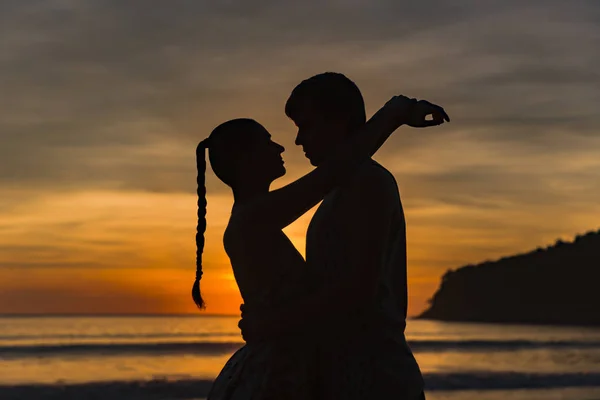 Gli amanti romantici che si abbracciano al crepuscolo con il tramonto sullo sfondo — Foto Stock