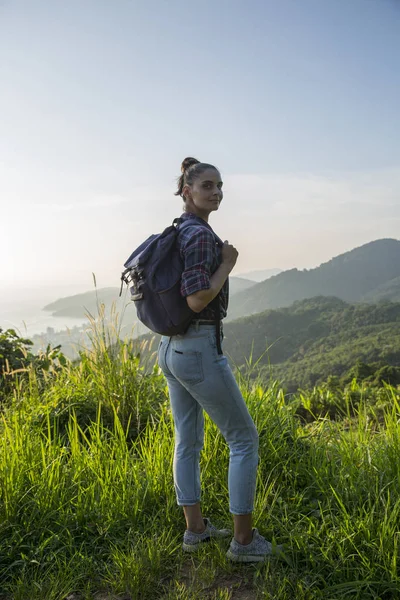 Hippi kız günbatımı sisli dağ tepe üzerinde zevk sırt çantası ile. Arka plan görünüm mockup üzerinde turist Gezgin.