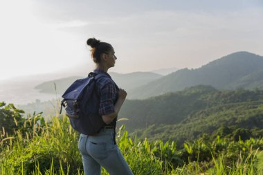 Hippi kız günbatımı sisli dağ tepe üzerinde zevk sırt çantası ile. Arka plan görünüm mockup üzerinde turist Gezgin.