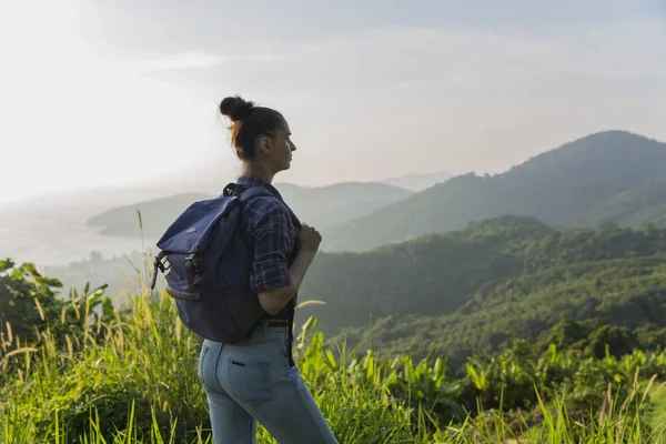 Hippi kız günbatımı sisli dağ tepe üzerinde zevk sırt çantası ile. Arka plan görünüm mockup üzerinde turist Gezgin.