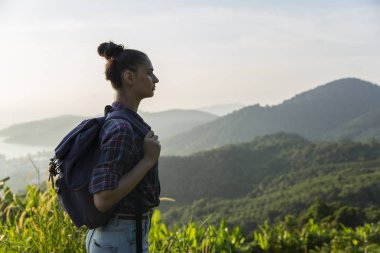 Hippi kız günbatımı sisli dağ tepe üzerinde zevk sırt çantası ile. Arka plan görünüm mockup üzerinde turist Gezgin.