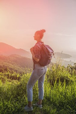 Hippi kız günbatımı sisli dağ tepe üzerinde zevk sırt çantası ile. Arka plan görünüm mockup üzerinde turist gezgin. Tonda, Instagram filtre