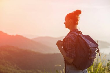 Hippi kız günbatımı sisli dağ tepe üzerinde zevk sırt çantası ile. Arka plan görünüm mockup üzerinde turist gezgin. Tonda, Instagram filtre