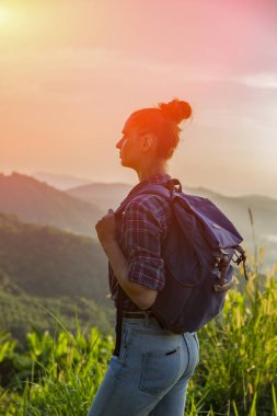 Hippi kız günbatımı sisli dağ tepe üzerinde zevk sırt çantası ile. Arka plan görünüm mockup üzerinde turist gezgin. Tonda, Instagram filtre