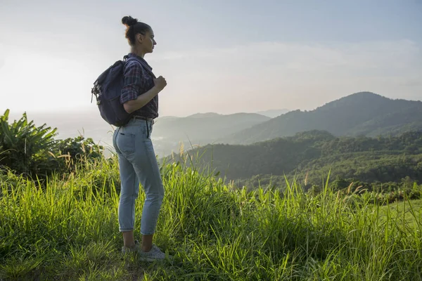 Hipster menina com mochila desfrutando do pôr do sol no pico da montanha nebulosa. Turista viajante em fundo vista mockup . — Fotografia de Stock