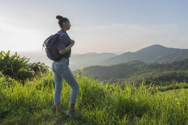 Hippi kız günbatımı sisli dağ tepe üzerinde zevk sırt çantası ile. Arka plan görünüm mockup üzerinde turist Gezgin.