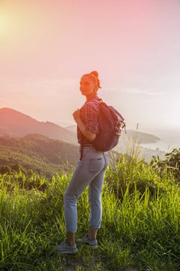 Hippi kız günbatımı sisli dağ tepe üzerinde zevk sırt çantası ile. Arka plan görünüm mockup üzerinde turist gezgin. Tonda, Instagram filtre