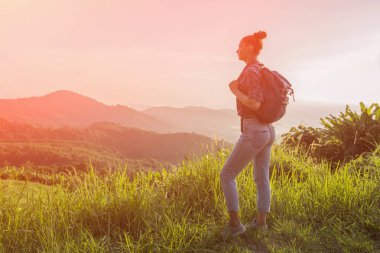 Hippi kız günbatımı sisli dağ tepe üzerinde zevk sırt çantası ile. Arka plan görünüm mockup üzerinde turist gezgin. Tonda, Instagram filtre