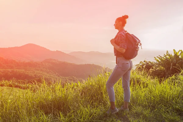 Hippi kız günbatımı sisli dağ tepe üzerinde zevk sırt çantası ile. Arka plan görünüm mockup üzerinde turist gezgin. Tonda, Instagram filtre