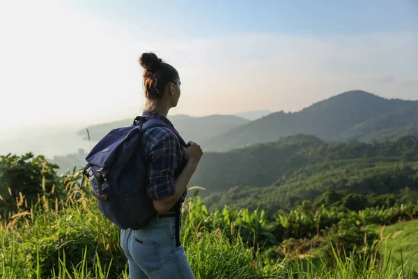 Hippi kız günbatımı sisli dağ tepe üzerinde zevk sırt çantası ile. Arka plan görünüm mockup üzerinde turist Gezgin.