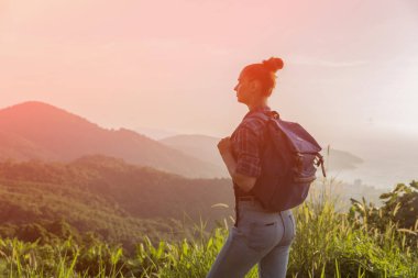 Hippi kız günbatımı sisli dağ tepe üzerinde zevk sırt çantası ile. Arka plan görünüm mockup üzerinde turist gezgin. Tonda, Instagram filtre