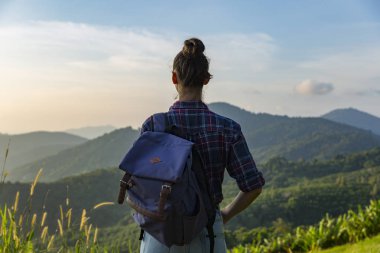 Hippi kız en yüksek dağında gün batımı zevk sırt çantası ile. Arka plan Vadisi manzara görünümü mockup üzerinde turist Gezgin.