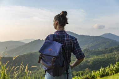 Hippi kız en yüksek dağında gün batımı zevk sırt çantası ile. Arka plan Vadisi manzara görünümü mockup üzerinde turist Gezgin.