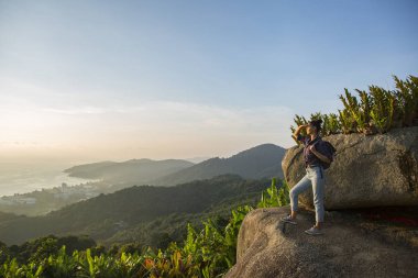Hippi kız en yüksek dağında gün batımı zevk sırt çantası ile. Arka plan Vadisi manzara görünümü mockup üzerinde turist Gezgin.