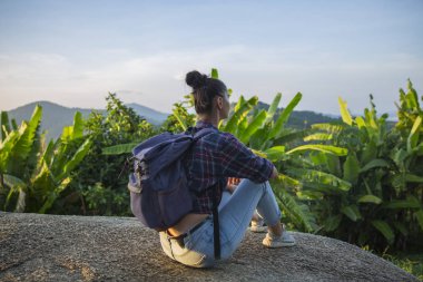 Hippi kız en yüksek dağında gün batımı zevk sırt çantası ile. Arka plan Vadisi manzara görünümü mockup üzerinde turist Gezgin.