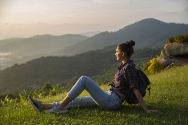 Hippi kız en yüksek dağında gün batımı zevk sırt çantası ile. Arka plan Vadisi manzara görünümü mockup üzerinde turist Gezgin.
