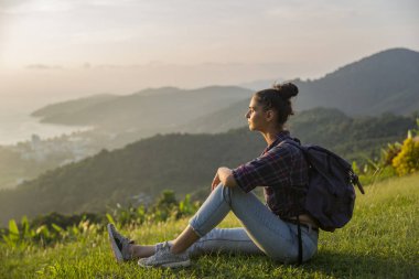 Hippi kız en yüksek dağında gün batımı zevk sırt çantası ile. Arka plan Vadisi manzara görünümü mockup üzerinde turist Gezgin.