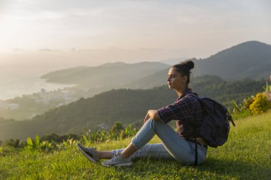 Hippi kız en yüksek dağında gün batımı zevk sırt çantası ile. Arka plan Vadisi manzara görünümü mockup üzerinde turist Gezgin.