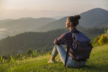 Hippi kız en yüksek dağında gün batımı zevk sırt çantası ile. Arka plan Vadisi manzara görünümü mockup üzerinde turist Gezgin.