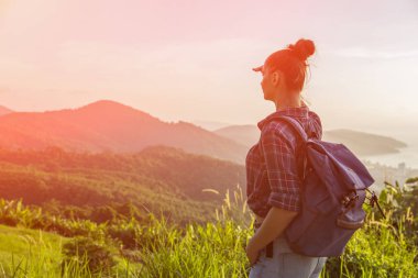 Hippi kız en yüksek dağında gün batımı zevk sırt çantası ile. Arka plan Vadisi manzara görünümü mockup üzerinde turist gezgin. Tonda. Instagram filtre