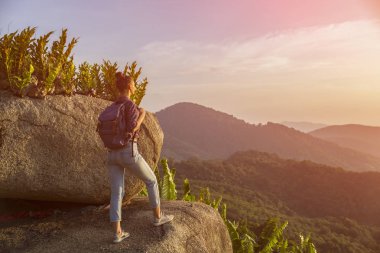 Hippi kız en yüksek dağında gün batımı zevk sırt çantası ile. Arka plan Vadisi manzara görünümü mockup üzerinde turist gezgin. Tonda. Instagram filtre