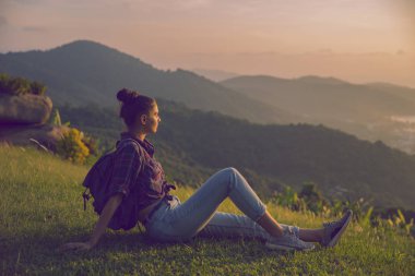 Hippi kız en yüksek dağında gün batımı zevk sırt çantası ile. Arka plan Vadisi manzara görünümü mockup üzerinde turist gezgin. Tonda. Instagram filtre