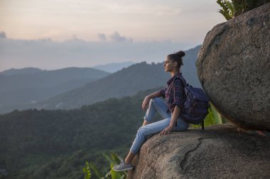 Hippi kız en yüksek dağında gün batımı zevk sırt çantası ile. Arka plan Vadisi manzara görünümü mockup üzerinde turist Gezgin.