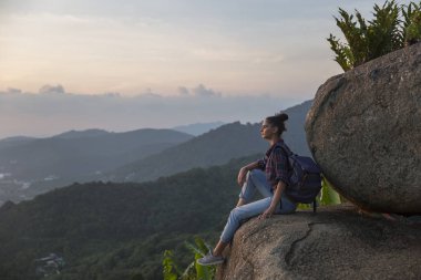 Hippi kız en yüksek dağında gün batımı zevk sırt çantası ile. Arka plan Vadisi manzara görünümü mockup üzerinde turist Gezgin.