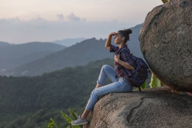 Hippi kız en yüksek dağında gün batımı zevk sırt çantası ile. Arka plan Vadisi manzara görünümü mockup üzerinde turist Gezgin.
