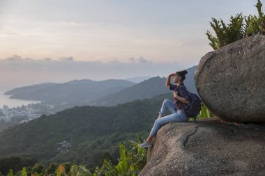 Hippi kız en yüksek dağında gün batımı zevk sırt çantası ile. Arka plan Vadisi manzara görünümü mockup üzerinde turist Gezgin.