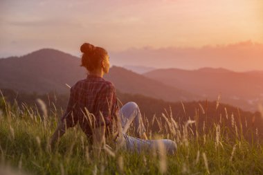 Hipster genç kız en yüksek dağında gün batımı zevk. Arka plan Vadisi manzara görünümü mockup üzerinde turist gezgin. Tonda, instagram vintage filtre.