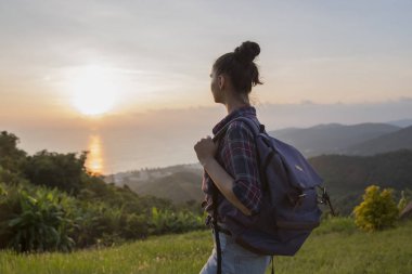 Hippi kız en yüksek dağında gün batımı zevk sırt çantası ile. Arka plan Vadisi manzara görünümü mockup üzerinde turist Gezgin.