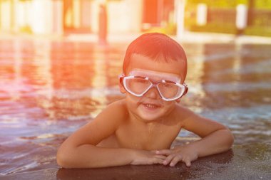 Gözlük takan bir havuz kenarında rahatlatıcı mutlu genç çocuk. Tonda