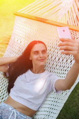 Cep telefonu hamakta bakarak rahat genç kadın. Tonda