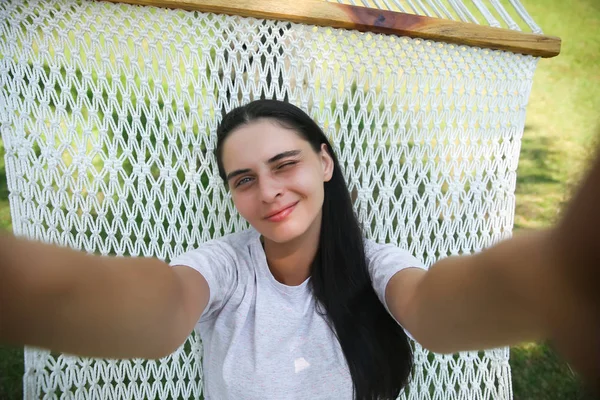 Mujer acostada en la hamaca y haciendo foto selfie en el teléfono inteligente al aire libre — Foto de Stock