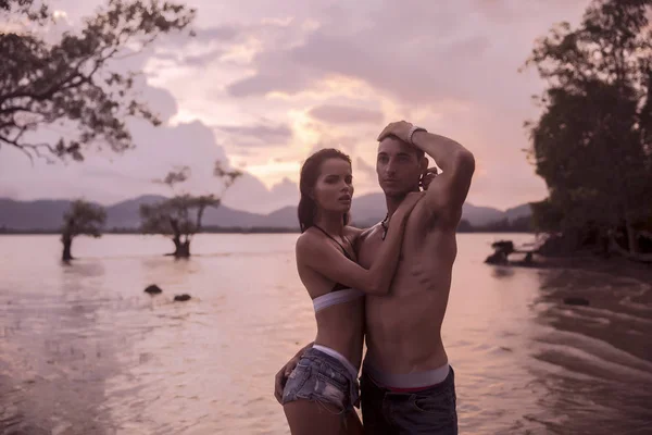 Im Freien ziemlich schöne junge romantische Paar verliebt Spaß haben und glücklich zusammen am Strand bei bunten Sonnenuntergang auf dem Hintergrund — Stockfoto