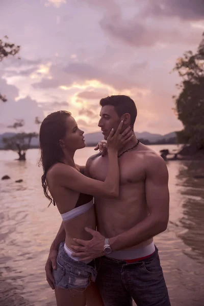 Im Freien ziemlich schöne junge romantische Paar verliebt Spaß haben und glücklich zusammen am Strand bei bunten Sonnenuntergang auf dem Hintergrund — Stockfoto