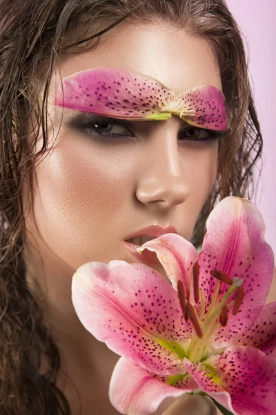 Ομορφιά πρόσωπο της η νεαρή όμορφη γυναίκα με λουλούδι. Γυναίκα που ακουμπά στο δέρμα. Κορίτσι σε ροζ φόντο — Φωτογραφία Αρχείου