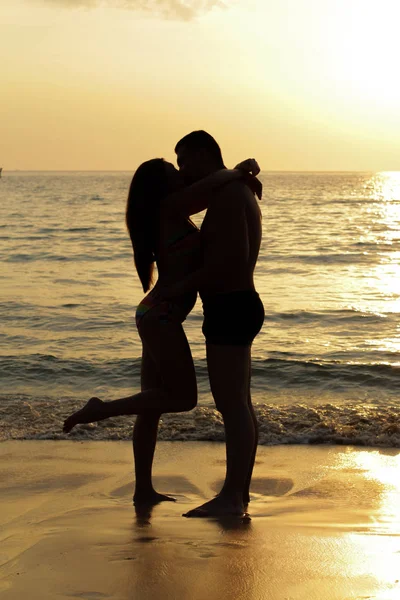 Vermelho tonificado foto de um casal em uma praia tropical ao pôr do sol — Fotografia de Stock