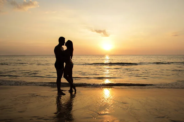 Vermelho tonificado foto de um casal em uma praia tropical ao pôr do sol — Fotografia de Stock