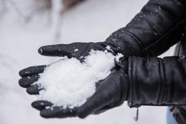 Sıcak kışlık kıyafetler giyen ve kar üfleyen genç kız.