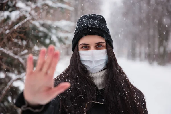 Тревожная женская внешность носит медицинскую маску, защищающую от коронавируса, опасающегося инфекции. Deadly coronavirus China 2019 2020-nCoV. Подпишите протест, протянув руку вперед — стоковое фото