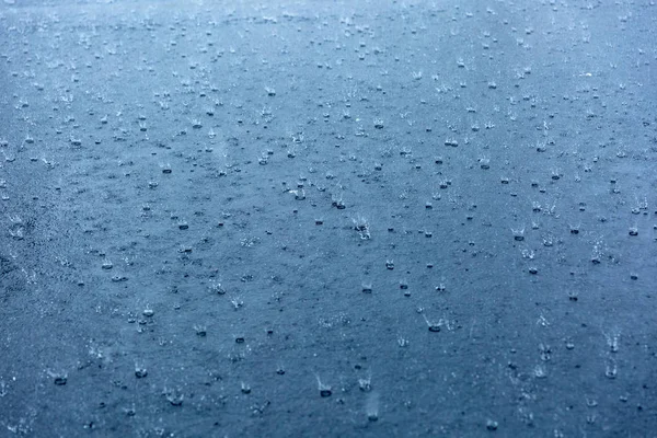 Gotas de chuva ondulando em uma poça com reflexão céu azul — Fotografia de Stock